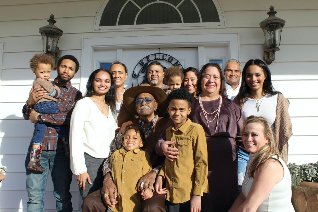 an interracial family smiling and posing for a photo in front of a house